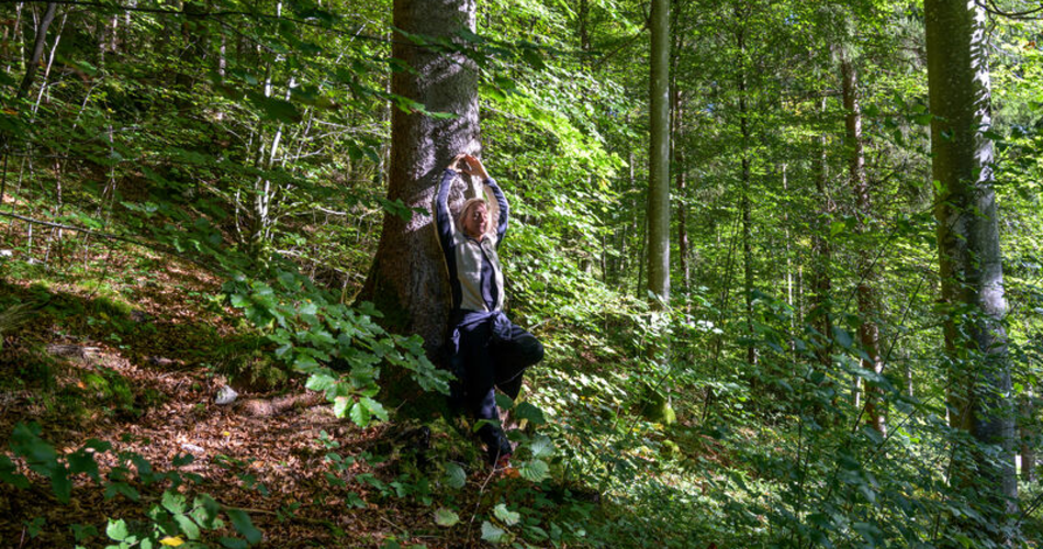 Weibliche Person lehnt an Baum im Wald | © BayTM/Gregor Lengler